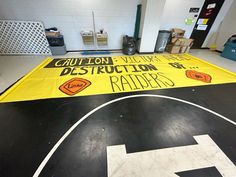 a yellow caution sign is on the floor in a room with black and white floors