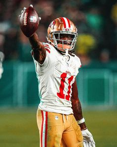 a man holding a football in his right hand and wearing a uniform with stripes on it