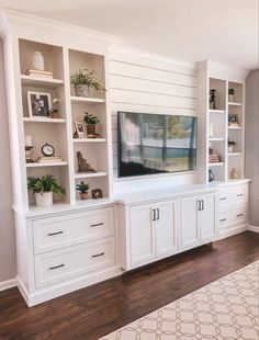 a living room with white bookcases and a flat screen tv mounted on the wall