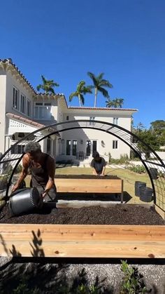 two men are working in the yard with some dirt on the ground and one is pouring water