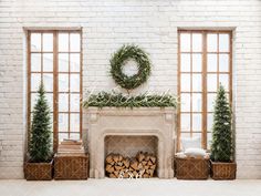 the fireplace is decorated with greenery and wreaths in front of two large windows