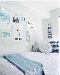 a bedroom with white walls and pictures on the wall above the bed, along with blue throw pillows