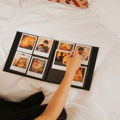 a woman laying in bed with her hand on the pages of a photo book that she is holding