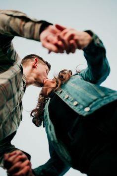 two people standing next to each other with their hands on the back of one another