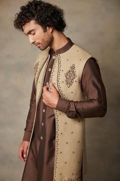 Gold longline bundi with floral embroidery. Paired with brown kurta and pant.
Component: 3
Pattern: Embroidered
Type Of Work: Floral
Neckline: Open
Sleeve Type: Full Sleeves
Fabric: Matka Silk, Cotton Silk
Color: Gold,Brown
Other Details: 
Embroidered bundi
Floral motifs
Occasion: Wedding - Aza Fashions Kurta Set For Men, Open Sleeve, Nehru Jackets, Kurta Set, Full Sleeves, Gold Floral, Floral Motifs, Embroidered Silk, Gold Design