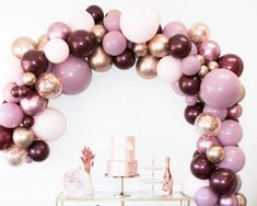 a table topped with lots of pink and gold balloons