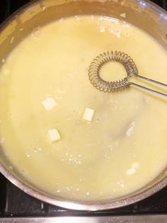 a metal bowl with some food in it on top of a stove burner and a whisk sticking out of the bottom