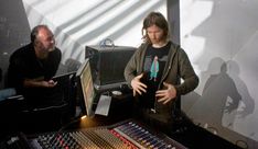 two men standing next to each other in front of sound equipment