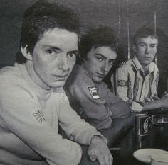 three young men sitting at a table with plates and cups in front of their faces