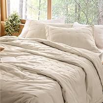 an unmade bed with white sheets and pillows in front of a large window overlooking the woods