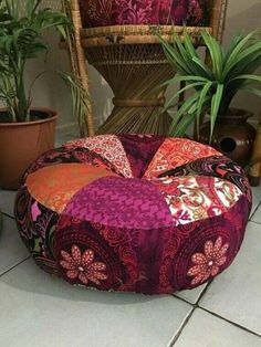 a colorful bean bag sits on the floor next to some potted plants and a wicker chair