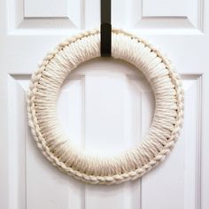 a white rope wreath hanging on the front door