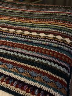 a multicolored crocheted blanket on top of a bed