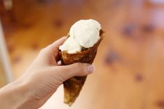 a hand holding an ice cream cone on top of a wooden table