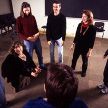 a group of people standing around each other in front of a blackboard and projector screen