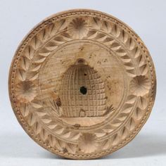 an old carved wooden object with holes in the center and leaves on it's sides