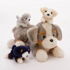 three stuffed animals sitting next to each other on a white surface with one laying down