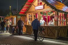 people are walking around in front of a small store with christmas lights on the roof