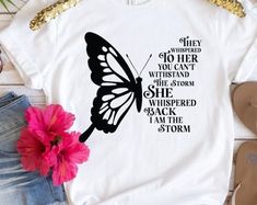 a white t - shirt with a black butterfly on it and the words, she is clothed