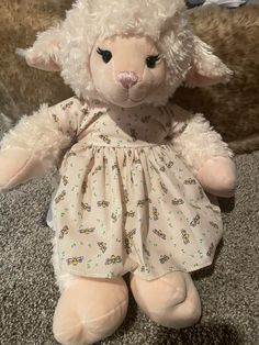 a stuffed sheep wearing a dress on the floor