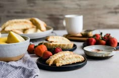 some fruit and pastries are sitting on the table next to plates with breads