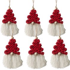 four red and white christmas decorations hanging from strings with tassels on top of them