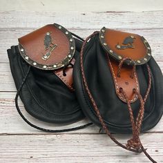 two black and brown leather saddles sitting on top of a wooden floor