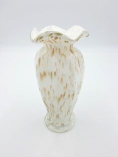 a white and brown vase sitting on top of a table