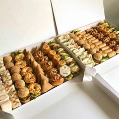 two boxes filled with different types of sandwiches and pastries next to each other on a table