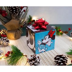 a mickey mouse christmas present on a table with pine cones and other holiday decorations around it