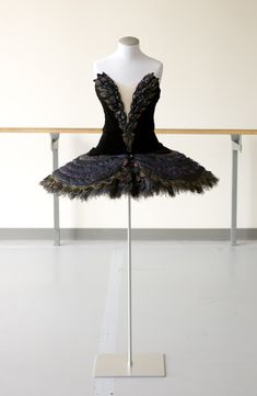 a mannequin wearing a black dress with feathers on it