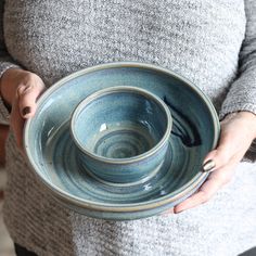 a woman holding a blue bowl in her hands with the lid up to show it's inside