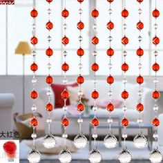 red glass beads hanging from the ceiling in front of a living room with white furniture