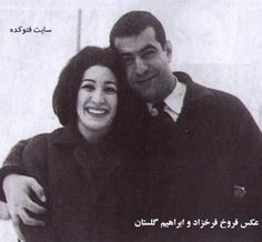 a man and woman hugging each other in front of a white wall with arabic writing on it