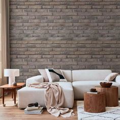 a living room with a white couch and wooden tables in front of a brick wall