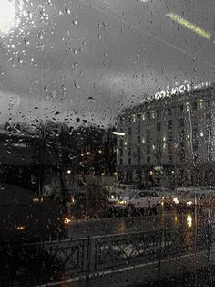 rain is falling on the window and cars are driving down the street in the city