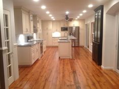 an empty kitchen and living room with hardwood floors in the middle is seen from the doorway