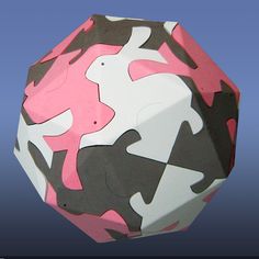 an origami ball with pink, black and white designs on the outside in front of a blue background