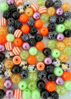 many different colored beads on a white surface with black, orange and green stripes in the middle