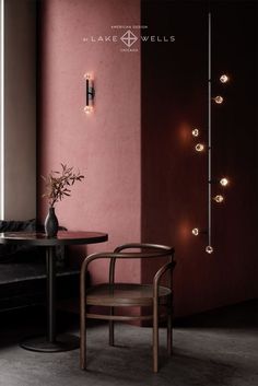 a chair and table in a room with lights on the wall behind it, next to a black couch