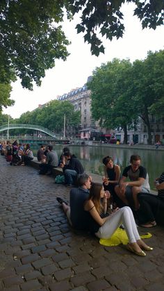 several people sitting on the side of a river