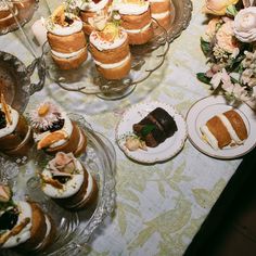 a table topped with lots of cakes and desserts next to plates filled with pastries