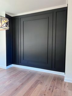 an empty room with black paneling and wood floors in the center is painted white