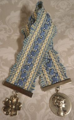 two pieces of blue and white knitted fabric with silver metal buttons attached to them