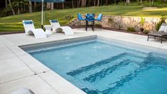 an empty swimming pool with lounge chairs around it