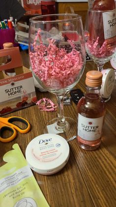 two wine glasses filled with pink confetti on top of a wooden table next to other items