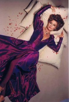 a woman in a purple dress laying on a pillow with blood all over her body