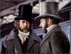 two men in top hats standing next to each other with one looking at the other