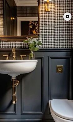 a white toilet sitting next to a sink in a bathroom under a mirror and lights