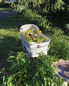 a white basket filled with flowers sitting in the grass